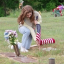 Girl Scout Addielou Tobiassen places a flag at a grave of a veteran